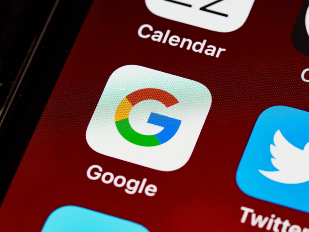 A close up image of a smartphone with the Google application in the center. 